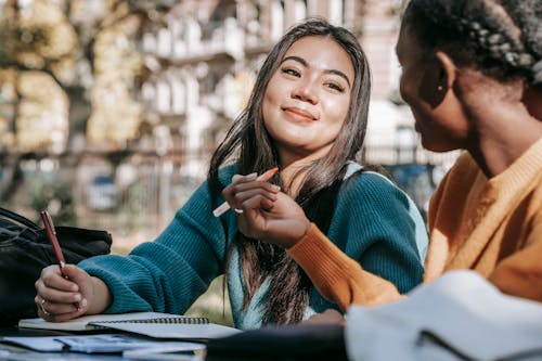 Free Glad diverse students taking notes while working on project Stock Photo