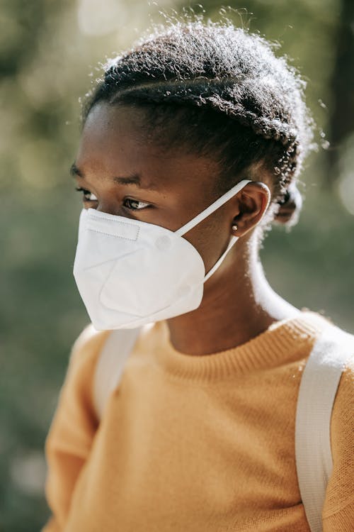 Ethnic student with backpack in protective mask in campus