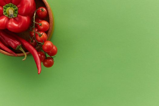 红甜椒、樱桃番茄和辣椒在绿色背景上，非常适合健康饮食概念