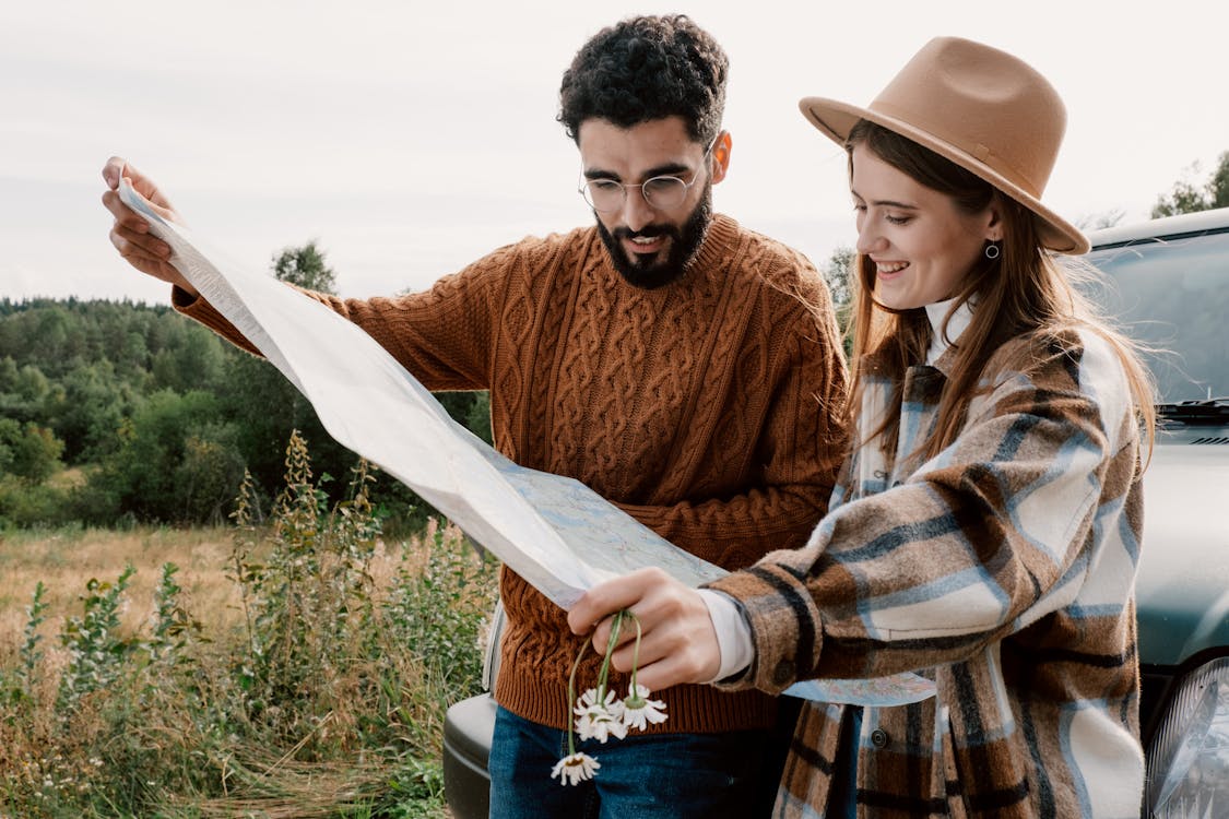 A man and a woman looking at a map while standing near a grass