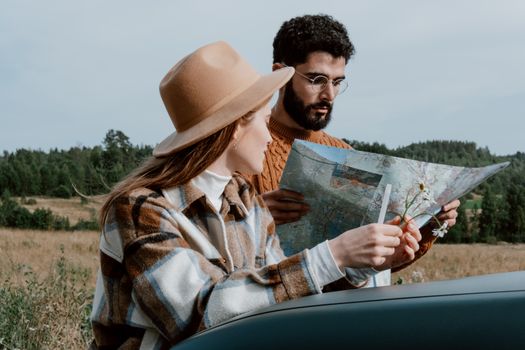 A couple outdoors examining a map, surrounded by nature, planning their adventure.