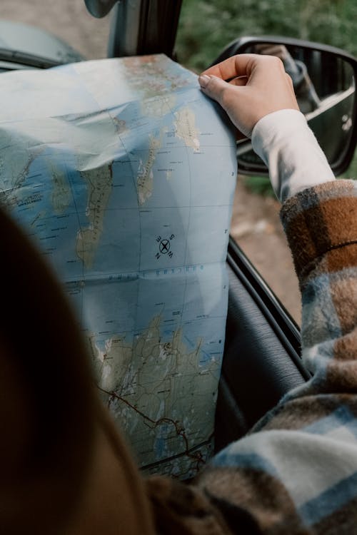 Person in Plaid Long Sleeve Shirt Holding a Map