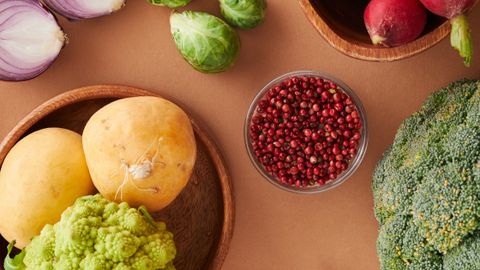 A colorful flat lay of fresh vegetables including asparagus, broccoli, and chili peppers on a brown surface.