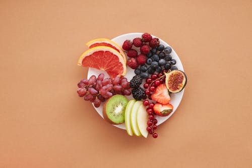 Rodajas De Naranja Y Fruta Verde Sobre Placa De Cerámica Blanca