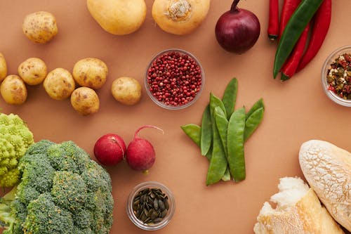 Top View of Vegetables and Bread Lying on Brown Surface 