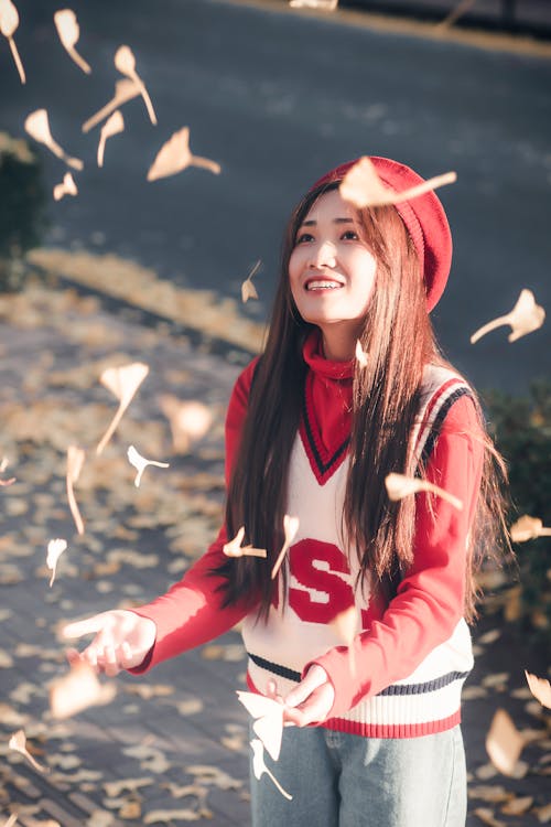 Woman in Red and White Shirt Catching Falling Leaves