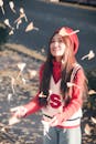 Woman in Red and White Shirt Catching Falling Leaves