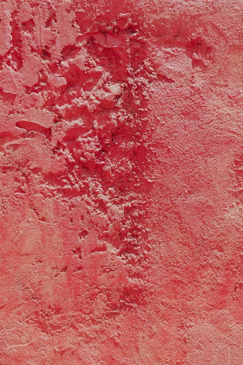 Textured background of red surface of wall covered with stucco with holes and scratches