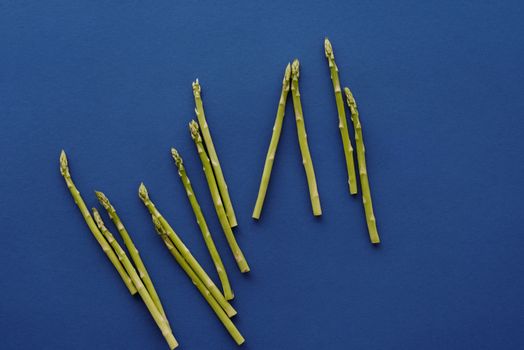 新鲜的芦笋茎在充满活力的蓝色背景上排列，凸显了其自然的颜色和纹理