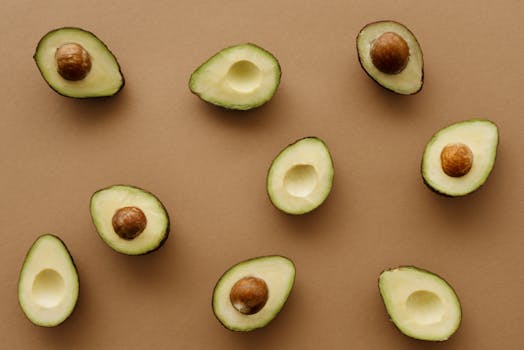 Aesthetic flat lay of ripe avocado halves arranged on a warm brown surface, showcasing freshness and healthy eating.