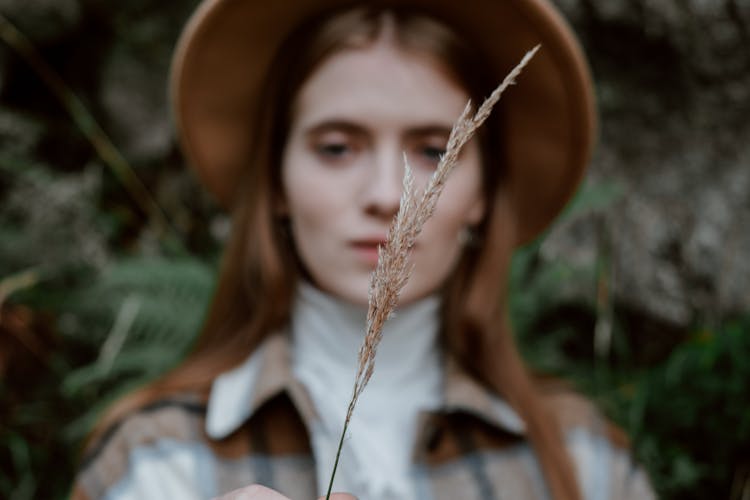 Woman In Hat Holding Brown Grass Flower