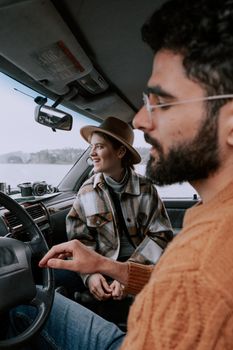 A couple shares a joyful moment inside a car during a winter road trip, capturing the essence of adventure and travel.