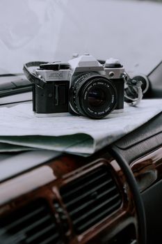 Close-up of vintage camera on a car dashboard with a map, ideal for travel themes.