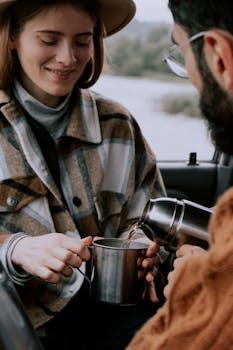 A couple enjoys a warm cup of tea together inside a car, creating a cozy atmosphere.