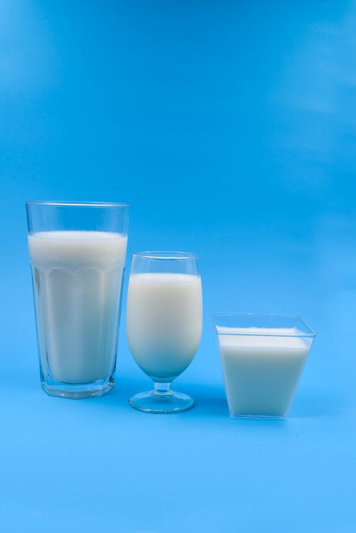 Glasses of Milk  on Blue Surface