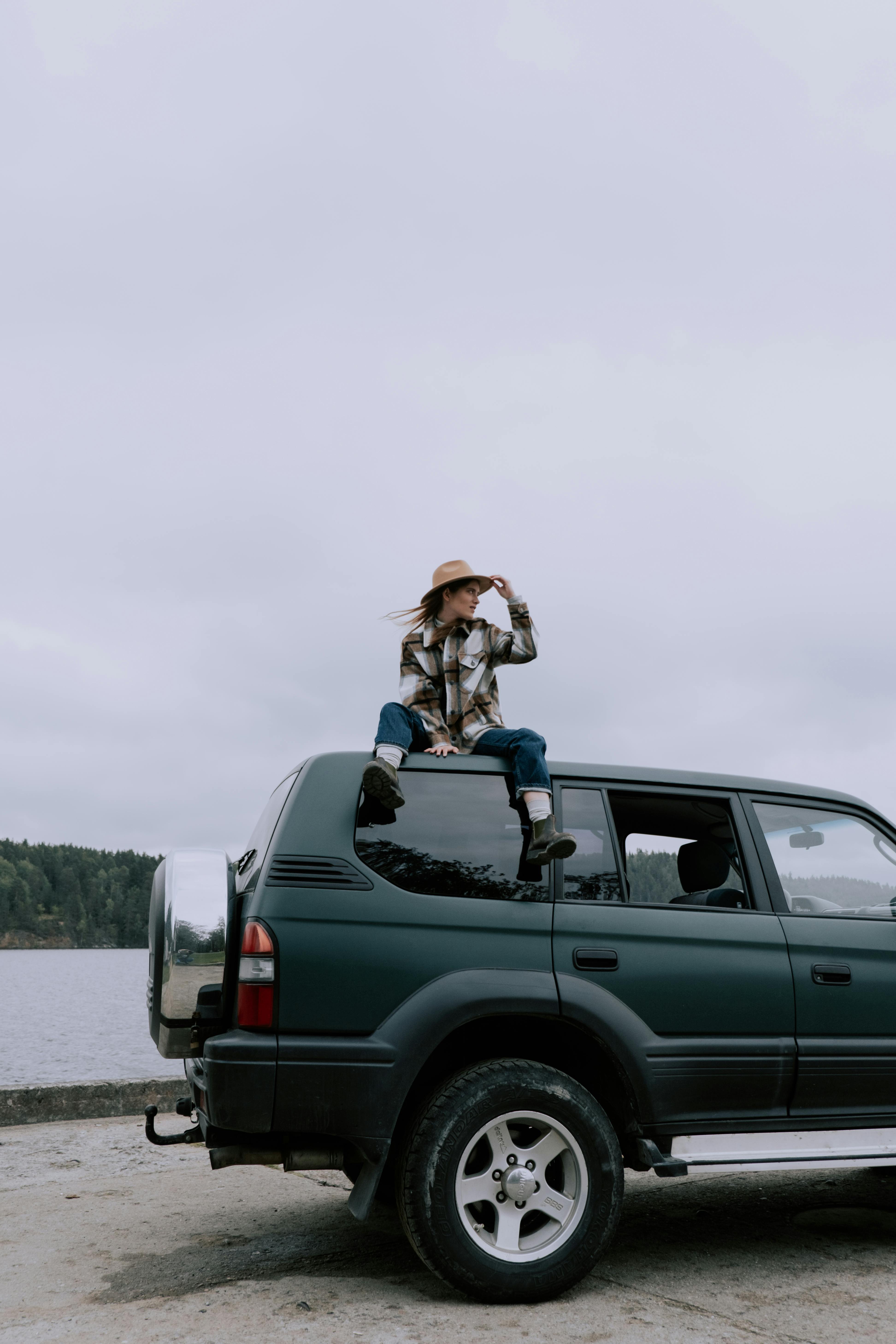 woman in brown hat sitting on vehicle roof