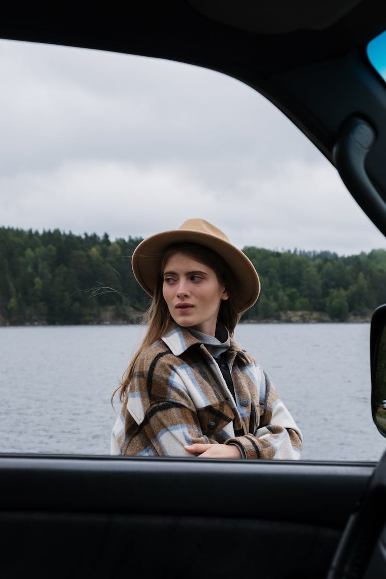 Woman In Brown Hat And Plaid Shirt Standing Outside A Car