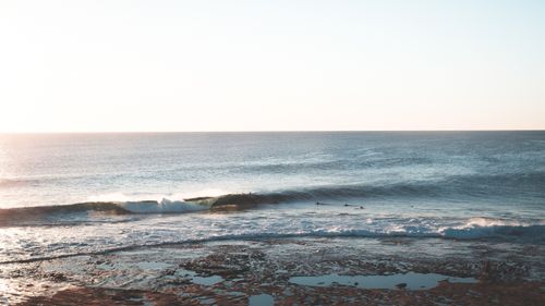Free Wet coast with foamy waves of ocean against cloudless sky with horizon line on summer evening with bright sun glares Stock Photo