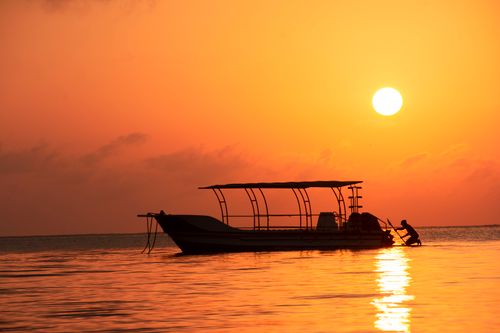 Free Silhouette of a boat and man during a stunning sunset in Mombasa, Kenya. Stock Photo