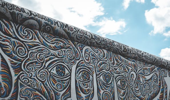 Colorful graffiti on a remnant of the Berlin Wall under a blue sky.