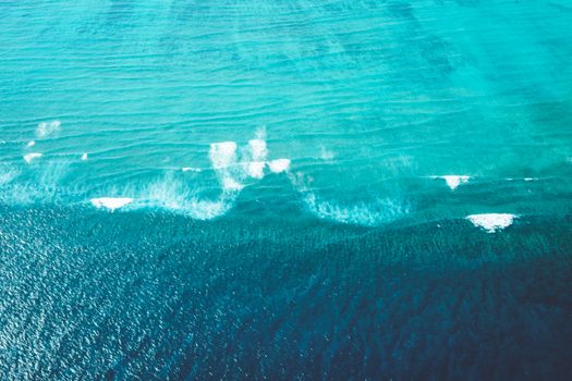 从空中俯瞰，阳光映照着碧绿的海浪，一幅宁静的海洋景象令人惊叹