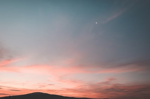 Picturesque scenery of sky with bright colors and silhouettes of mountains at sundown