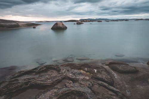 Amazing scenery of shallow rocky shore with tranquil seawater under majestic cloudy sky