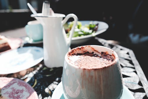 Free Tasty fresh hot chocolate in white cup served on metal table with fresh salad on sunny weather Stock Photo