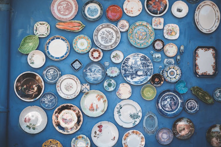 Set Of Many Decorative Plates On Blue Wall