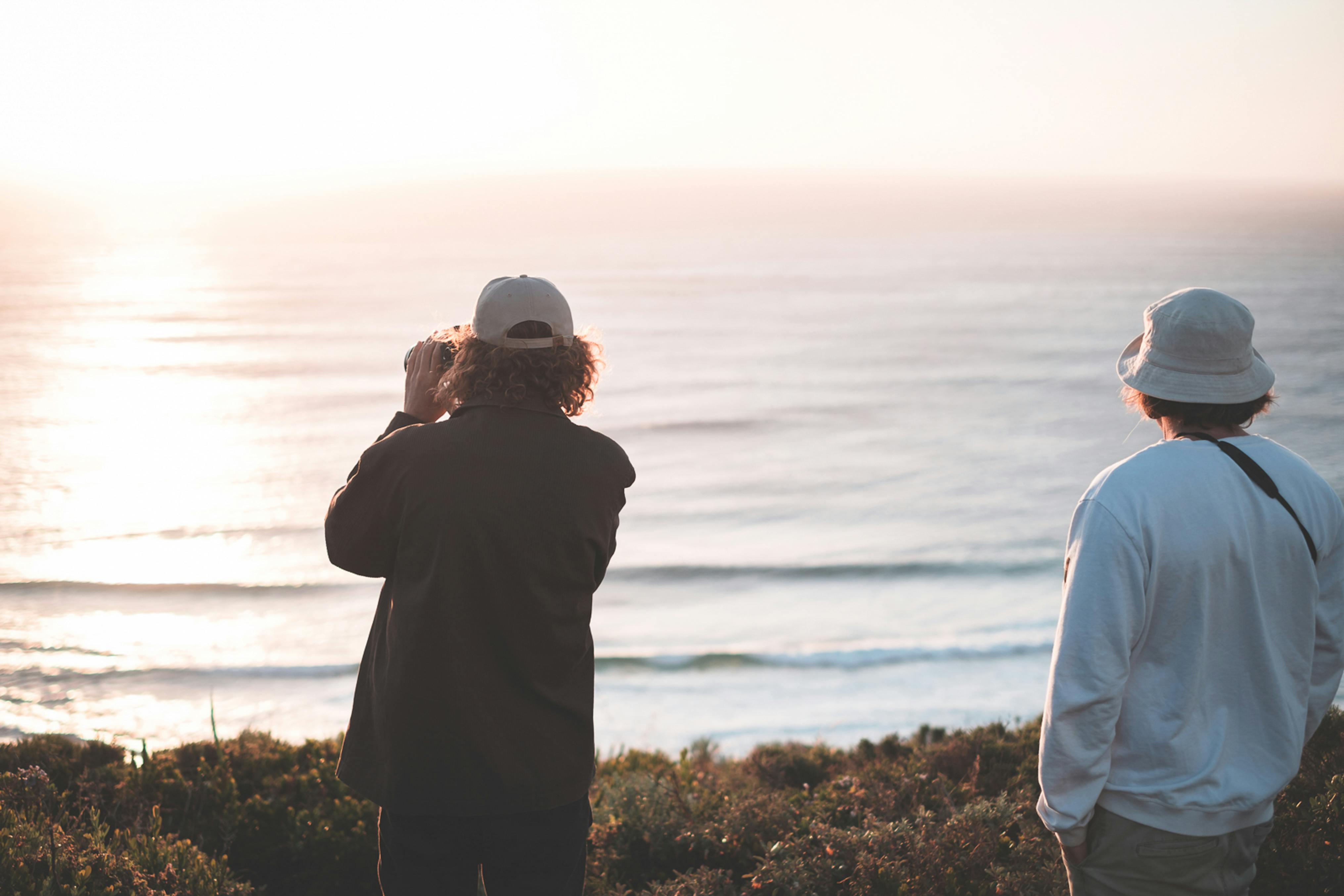 unrecognizable men admiring amazing rippling sea in early evening