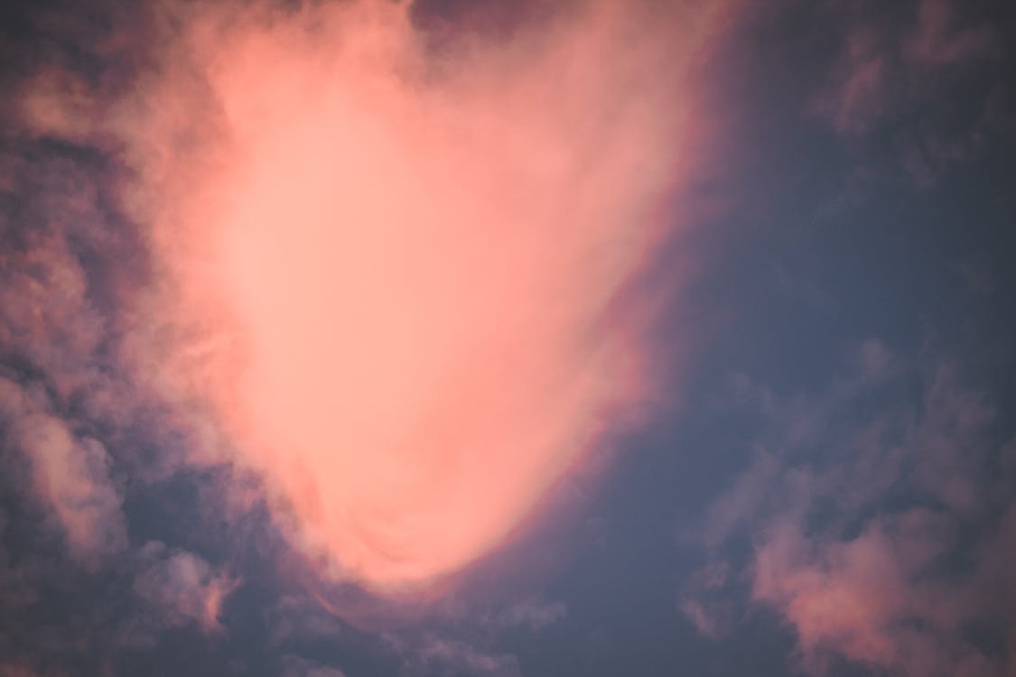 From below scenery of fluffy pink clouds floating in blue sky on fair weather