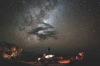 Traveler standing on car at starry night