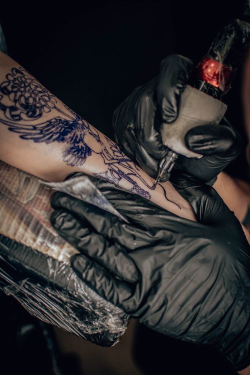Free Close-up shot of a tattoo artist's hands creating intricate designs on an arm. Stock Photo
