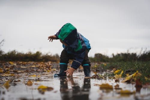 Free Kid Wearing Jacket Reaching for the Ground Stock Photo