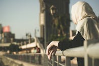 一位戴着头巾的女人从桥上俯瞰城市景观，感受着城市的宁静