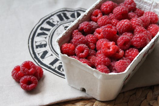 A close-up of fresh, ripe raspberries in a cardboard container, perfect for a healthy snack.