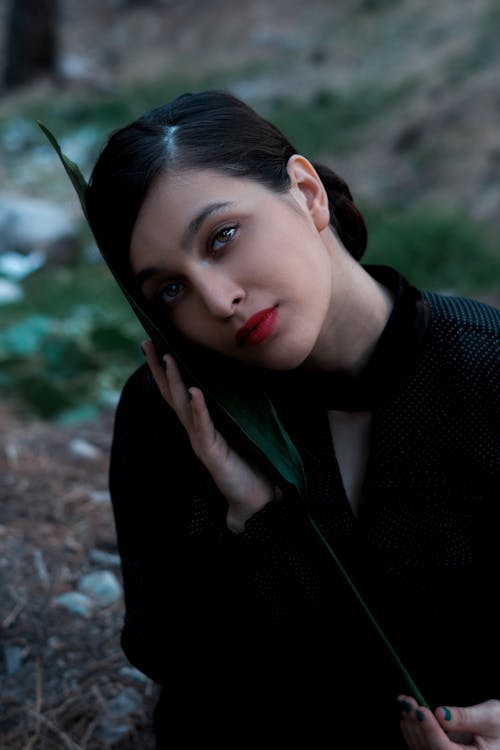 Gorgeous woman touching face with leaf in nature