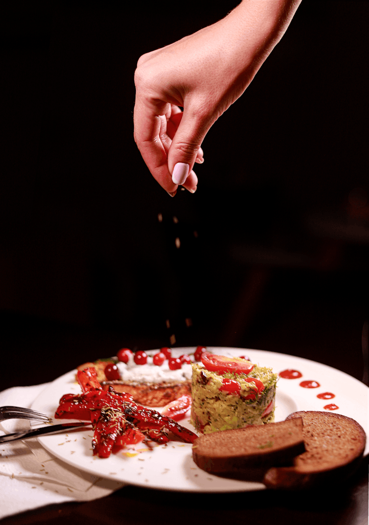 Person Seasoning Food On Plate