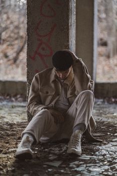 一个年轻人孤独地坐在一根布满涂鸦的柱子上，引人深思