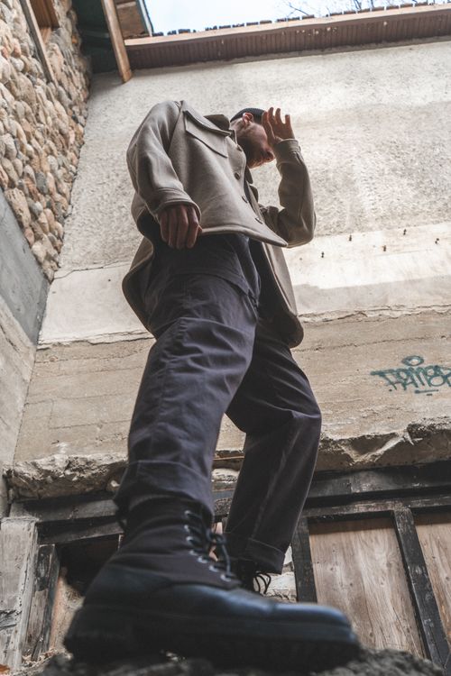 Free Dynamic low angle shot of a man in boots and coat standing outdoors against a building in Ottawa. Stock Photo