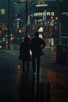 雨夜的多伦多市中心，一对夫妇在灯光下行走