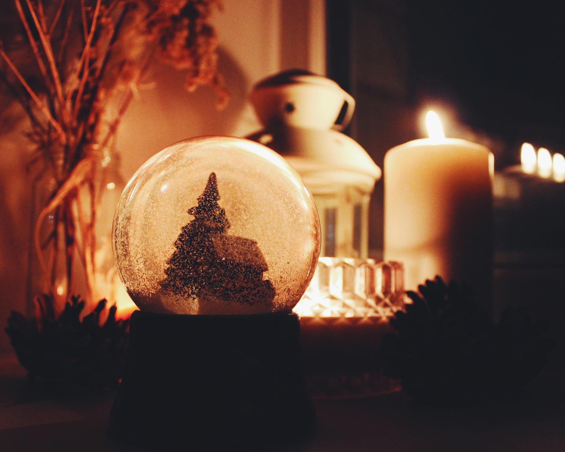 Warm and inviting snow globe scene with candles, perfect for holiday vibes.