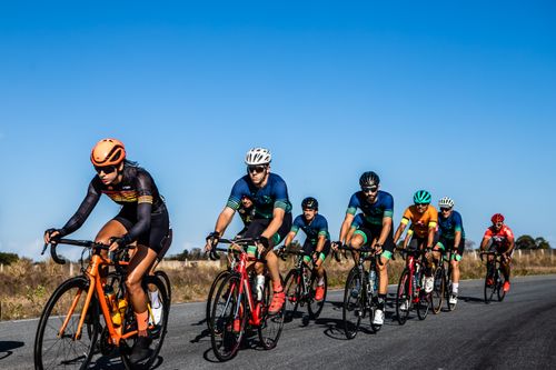 Free Energetic group of cyclists racing under a clear blue sky in João Pessoa, Brazil. Stock Photo