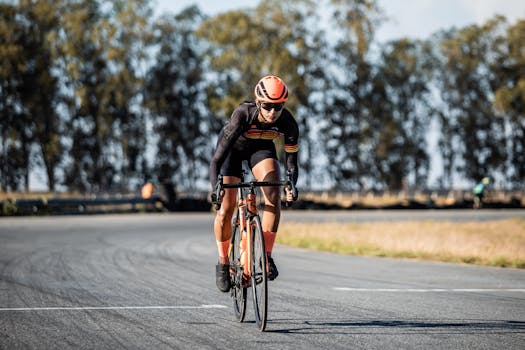 A focused cyclist in gear rides on a curvy road, surrounded by nature, on a sunny day.