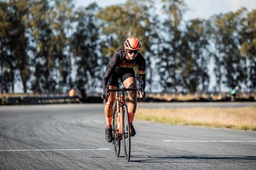 Free A focused cyclist in gear rides on a curvy road, surrounded by nature, on a sunny day. Stock Photo