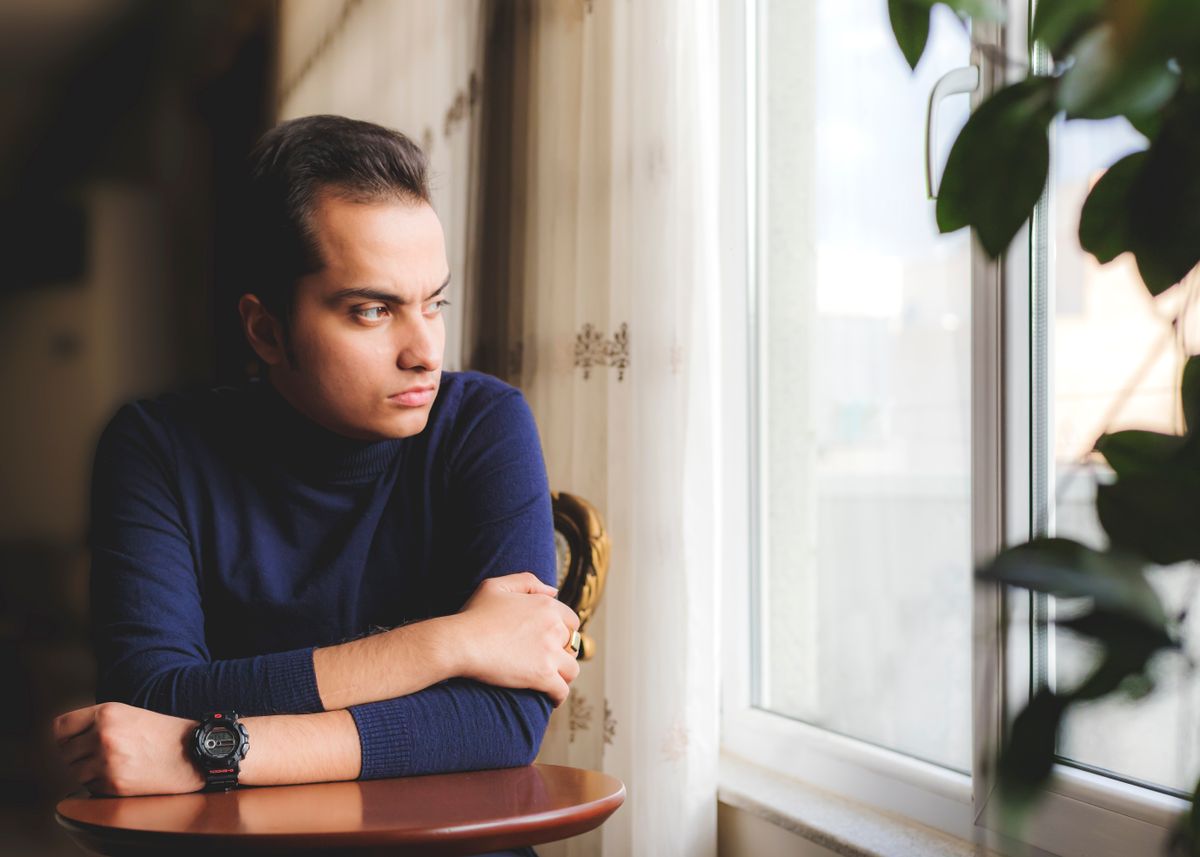 A man leaning on a table, gazing out a window — photo by Ramin Aghaei on Pexels