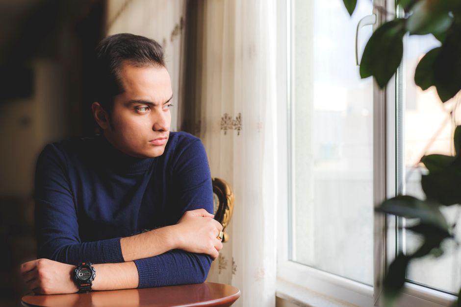 Person standing at a window looking out — ibogaine is not a cure for addiction; it opens a window of reduced craving during which lasting change becomes more possible