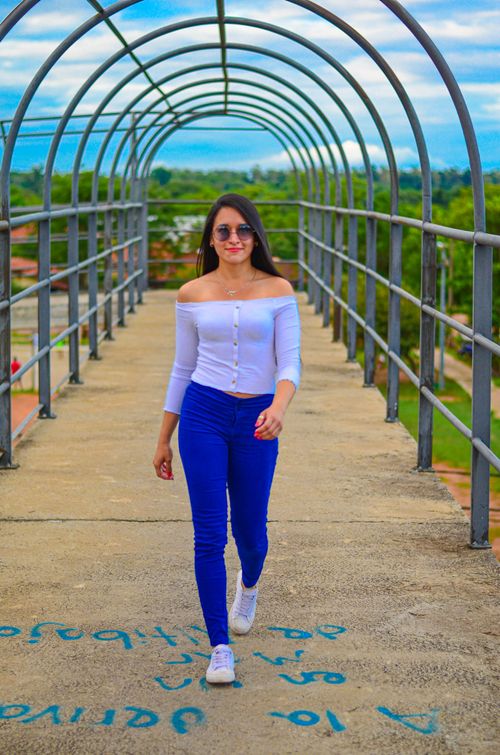 Free Stylish woman in sunglasses walking confidently on a city footbridge. Stock Photo
