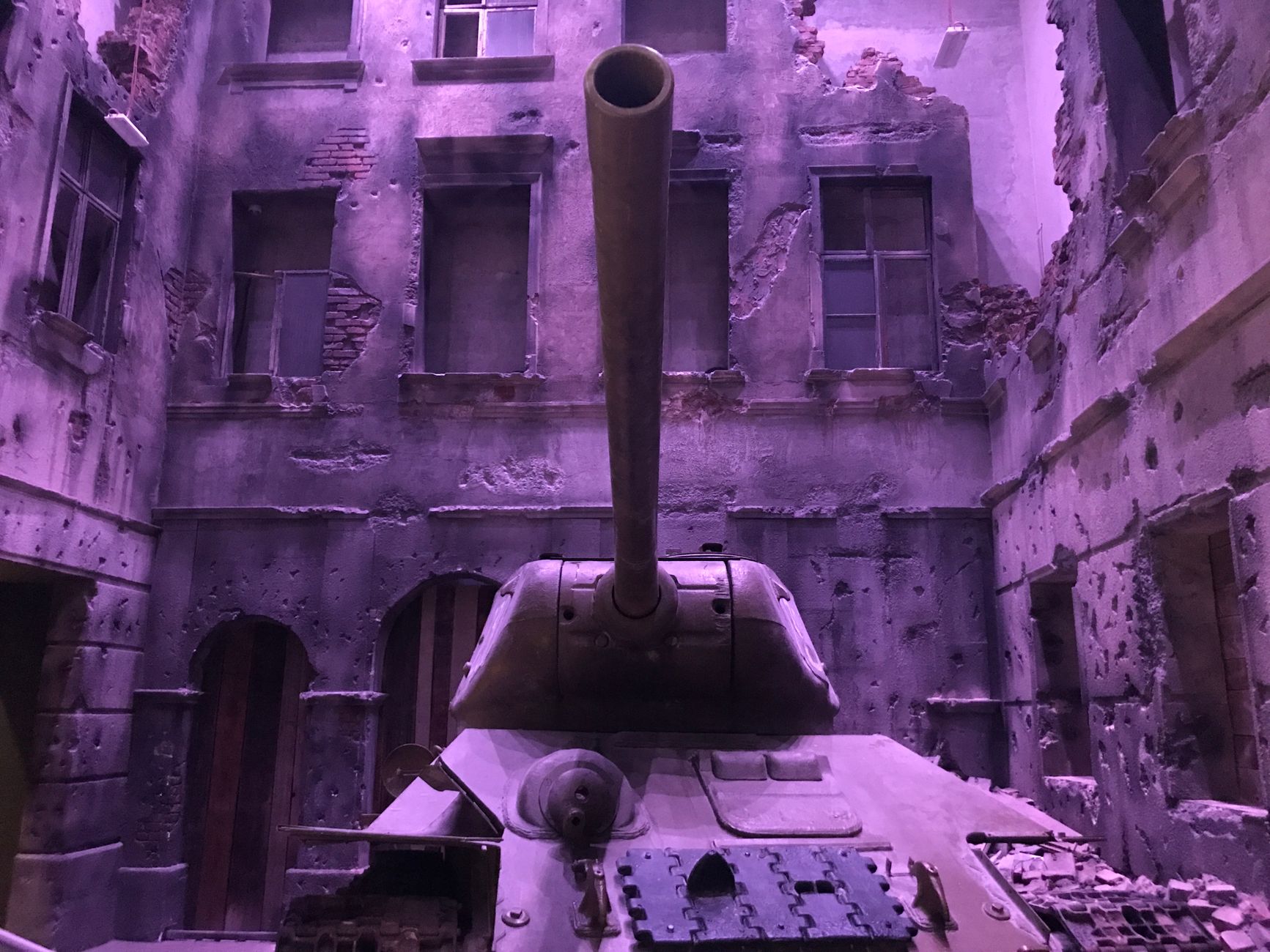A vintage tank amidst an urban backdrop of damaged and abandoned architecture.