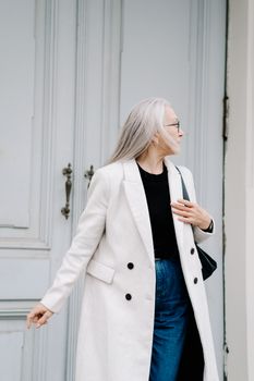 一位白发、身穿白外套的老练资深女性正在户外摆姿势